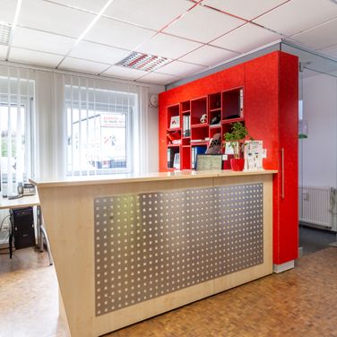 Theke-am-Empfang-einer-Firma-in-einem-hellen-Raum-mit-roter-Wandfarbe